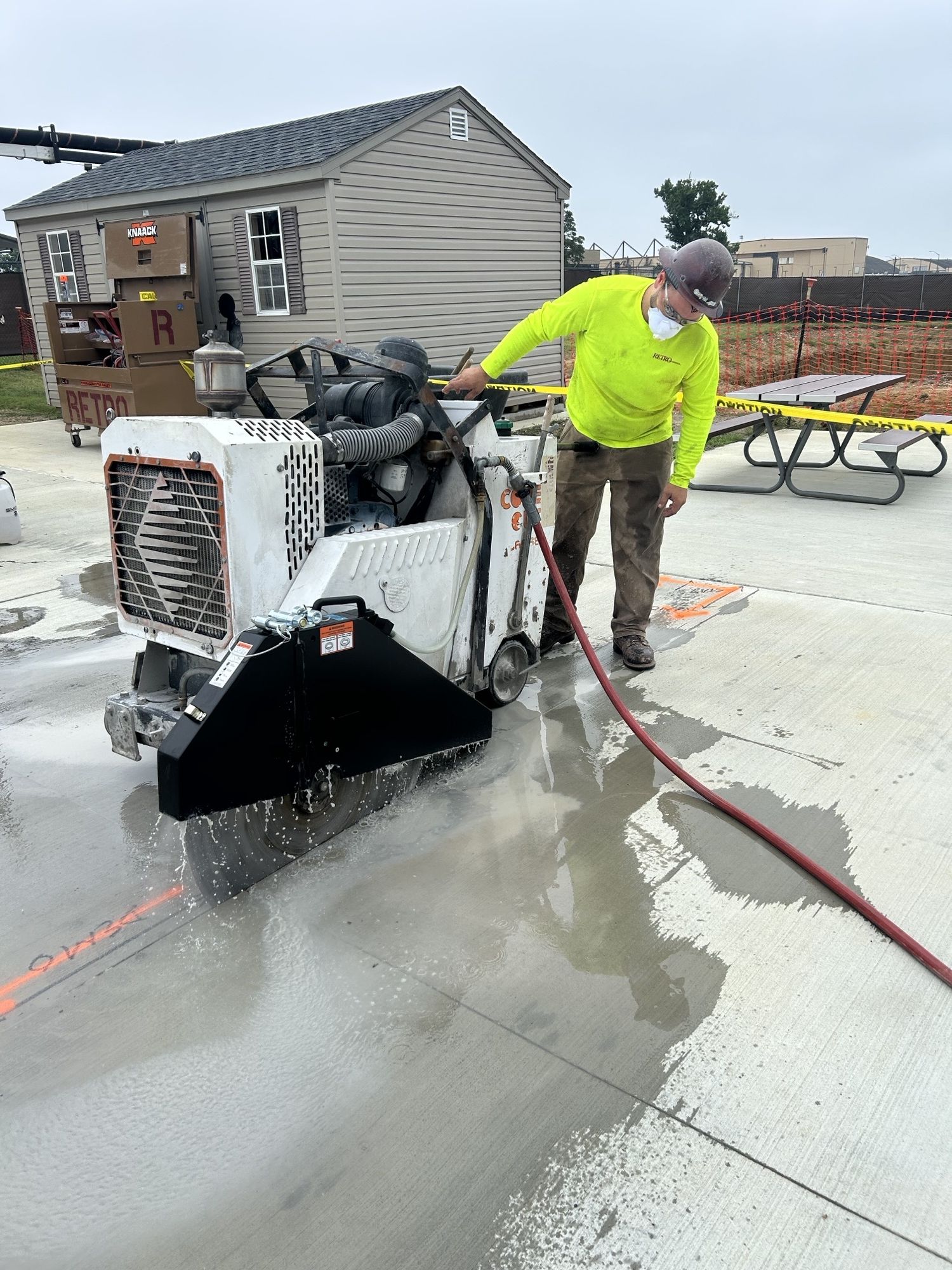 RETRO crew member wet-cutting a concrete slab with a walk-behind flat saw next to a RETRO job box