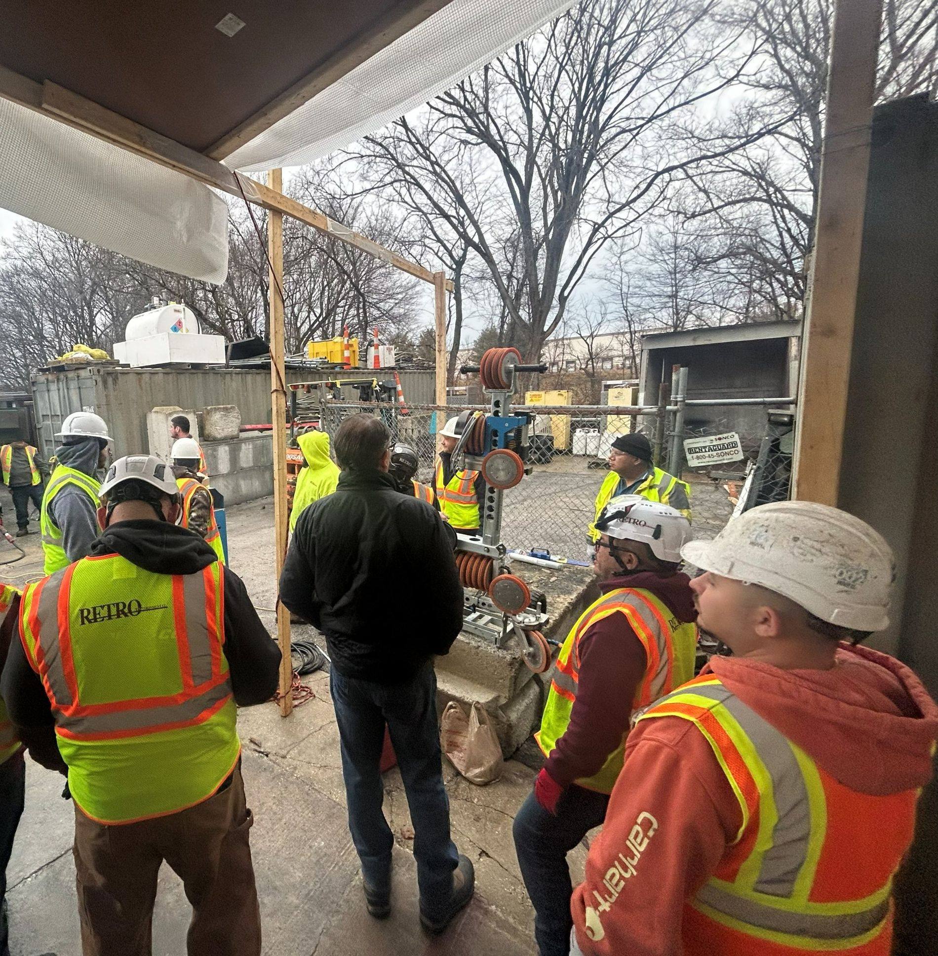 RETRO crew members in hard hats and RETRO safety vests gathered for a wire saw demonstration