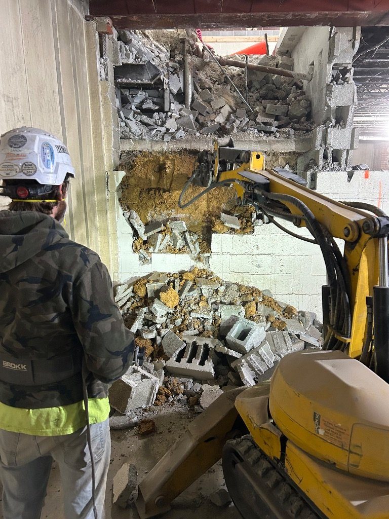 RETRO operator watching from a distance as the BROKK® remote-controlled machine breaks out a concrete block wall